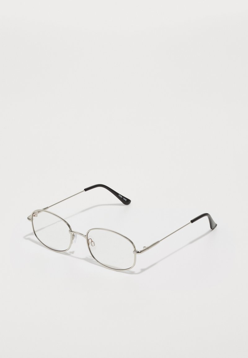 Lunettes en métal avec une monture ovale, des biseaux argentés et des verres transparents. Branches droites et fines avec des embouts noirs, design minimaliste.