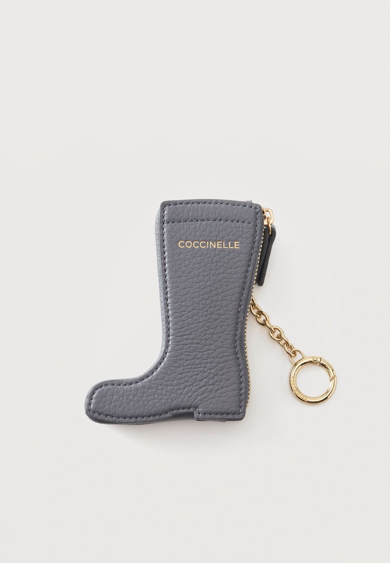 Porte-clés en cuir gris en forme de botte avec fermeture éclair dorée et chaîne, embossé du nom de la marque Coccinelle.