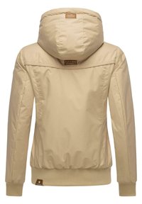 Beige jas met capuchon, gemaakt van gladde stof. Geribbelde manchetten en onderrand, met een klein merkembleem nabij de onderrand. Minimalistisch ontwerp.