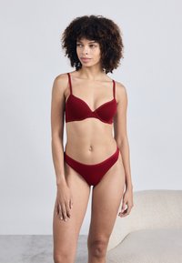 Κόκκινο σουτιέν και ταιριαστό στυλ μπικίνι εσώρουχο φτιαγμένο από λεία ύφανση. Το σουτιέν διαθέτει καλυμμένα cups, ρυθμιζόμενους ιμάντες και μια διακριτική σχεδίαση ραφής.