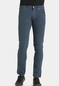Chino di cotone blu navy con vestibilità slim, cinque tasche e passanti per cintura. Finito con una texture liscia e dettagli di cucitura minimi.