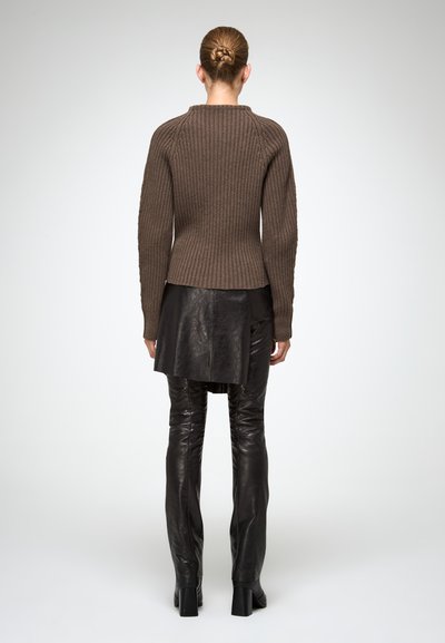 Maglione a coste marrone con collo alto, design aderente e maniche lunghe, abbinato a pantaloni in pelle nera e scarpe con tacco.