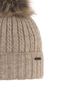 Bonnet en tricot beige avec une texture côtelée, doté d'un gros pompon en fourrure sur le dessus et d'une petite étiquette logo noire sur le côté.