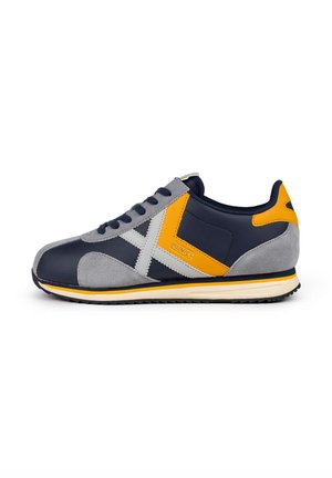Heren sneaker met een marineblauwe bovenkant en grijze en gele accenten, van suede en synthetische materialen, een ronde neus en een gestructureerde buitenzool.