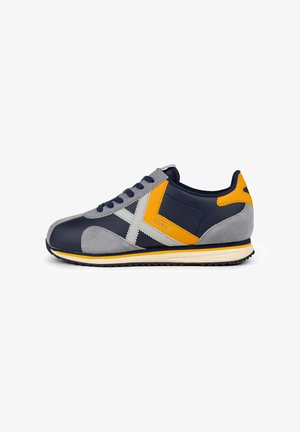 Men's sneaker featuring a navy upper with grey and yellow accents, suede and synthetic materials, a rounded toe, and a textured outsole.