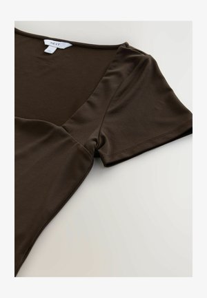 Smeđi kratki rukav majica izrađena od glatkog, rastezljivog materijala s V-izrezom. Ima opušteni kroj i suptilne detalje šivanja.