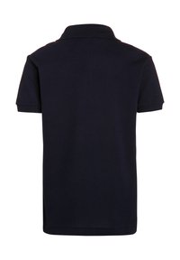 Granatowa koszulka polo z teksturowanej tkaniny, krótki rękaw i klasyczny kołnierzyk. Posiada boczne rozcięcia dla swobody ruchu. Brak widocznych logo.