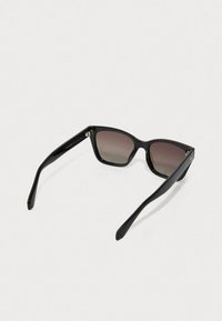 Óculos de sol estilo gato preto com lentes degradé, armação de plástico suave e hastes finas. Apresenta um pequeno logotipo em destaque na dobradiça.