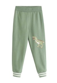Zielone dziecięce spodnie dresowe z prążkowanym pasem i mankietami z białymi paskami oraz z rysunkowym dinozaurem na prawej udzie.