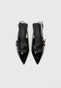 Črne lakirane slingback petke s koničastimi prsti, prečnimi trakovi in zlatimi zaponkami. Gladka tekstura, minimalističen dizajn.