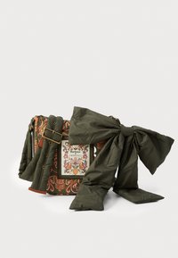 Quiltowana torba w pomarańczowy wzór kwiatowy z zielonymi akcentami, z dużą kokardą i naszywką z napisem "Barbour FARM RIO." Regulowany pasek.