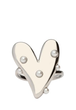 Anillo plateado en forma de corazón con superficie lisa y cinco pequeñas perlas blancas incrustadas dispuestas asimétricamente en la parte delantera.