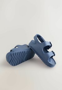 Sandale de cauciuc albastre cu talpă texturată, curele reglabile, design deschis și finisaj neted, potrivite pentru purtarea casual.