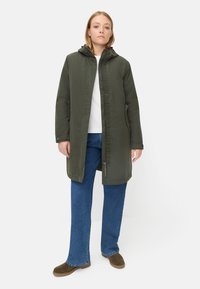 Oliven grøn hætteparka med lynlås og trykknaplukning, der har sidelommer, en afslappet pasform og en glat tekstur. Kombineret med blå jeans.