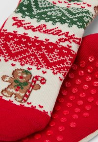 Červené a krémové pletené ponožky s motivem perníkového muže, kostkovanými vzory a texturovanými červenými gripovými tečkami na podrážce.