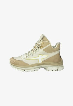 Beige en crème sportieve schoen van textuurmesh en rubbermaterialen, met een gele logo, ronde veters en een profielzool.