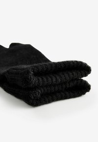 Schwarze gestrickte Socken, gefaltet, mit gerippter Textur und glatter Oberfläche. Das Material wirkt weich und flexibel mit einem schlichten Design.