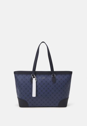 Sac fourre-tout bleu marine en tissu à motifs, avec une base unie, des accents noirs contrastés, deux poignées robustes et une étiquette blanche.
