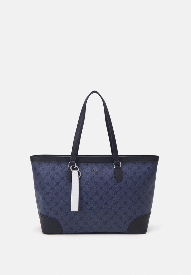 Sac fourre-tout bleu marine en tissu à motifs, avec une base unie, des accents noirs contrastés, deux poignées robustes et une étiquette blanche.