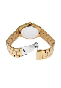 Zelta tonis nerūsējošā tērauda pulkstenis ar gludu saiti, apaļu korpusu un pulētu sprādzi. Aizmugurē ir iegravēti teksti ar modeļa detaļām.