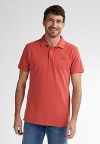 Rode polo shirt van katoen, met een drieknoopssluiting, korte mouwen en een klein logo op de linkerkant van de borst.