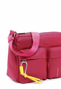 Sac à épaule en tissu rose avec une fermeture éclair, deux poches avant et une sangle d'accent jaune. Comprend du matériel métallique et une surface texturée.