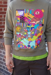 Olivgrön sweatshirt med en livlig, flerfärgad grafisk design med abstrakta mönster och karaktäristiska inslag. Ribbad mudd och nederkant.