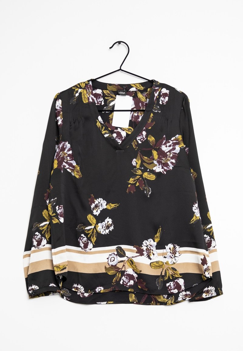 Blouse noire à manches longues avec un col en V, imprimé floral en blanc, jaune et marron, et des rayures beige et blanches près de l'ourlet, suspendue à un cintre noir.