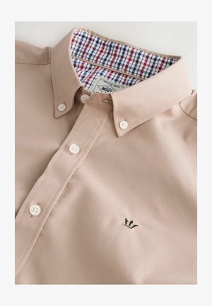 Beige skjorte med krave i bomuldsblanding med hvide knapper. Indersiden har et rødt, blåt og hvidt ternet mønster. Broderet logo på forsiden.