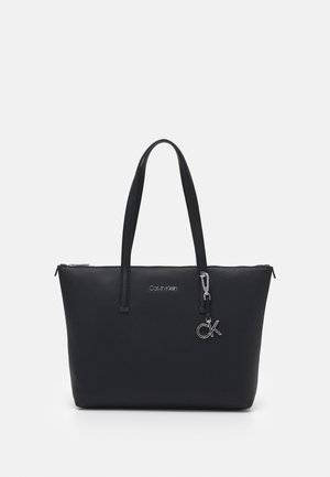 Sort Calvin Klein tote taske med to håndtag, en lynlåslukning og en sølv CK logo vedhæng på forsiden.