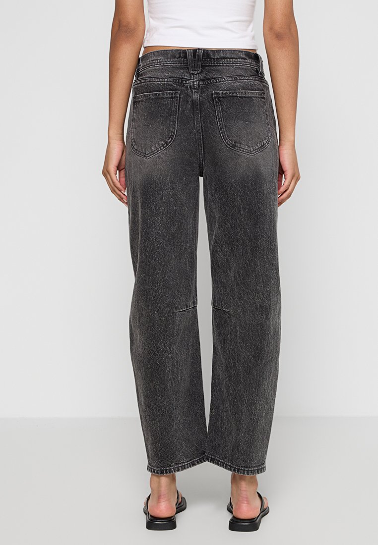Jeans in denim nero a vita alta con una vestibilità ampia, texture sbiadita e gambe dritte. Presenta due tasche posteriori e cuciture a vista.
