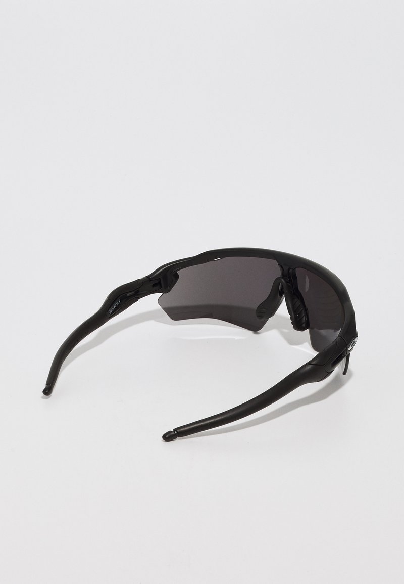 Black sunglasses with a wrap-around design, dark lenses, and flexible rubber arms. Features a molded nose bridge for a secure fit.