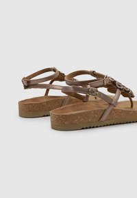 Sandales en liège marron avec des brides tressées et des boucles réglables. Semelle intérieure Texturée avec une semelle rainurée pour une meilleure adhérence.
