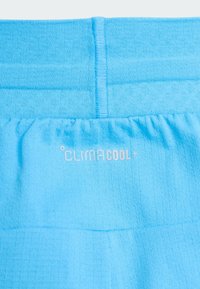 Shorts de sport bleu clair en tissu doux et texturé. Dotés d'une ceinture élastique et du logo imprimé "CLIMACOOL+" en blanc.