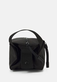 Bolsa de nailon negra con cierre de cremallera, asa corta y una correa frontal con botón a presión. Forma cuadrada compacta con una superficie texturizada.