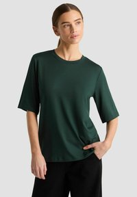 Mørkegrøn kortærmet t-shirt med rund hals, lavet af glat stof, med en afslappet pasform og minimalistisk design.