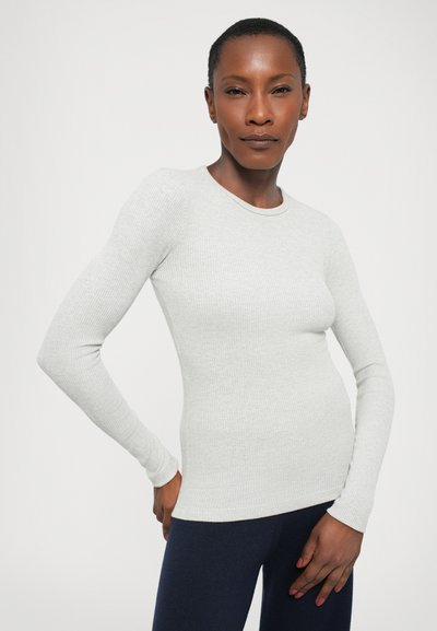 Light gray long-sleeve ribbed knit top with a round neckline and fitted design, paired with navy leggings. Smooth texture throughout.
