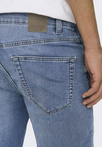 Lichtblauwe denim jeans met een zichtbare achterzak en stikseldetails. Beschikt over een leren label op de tailleband. Casual pasvorm ontwerp.