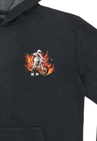 Černá mikina s kapucí s grafikou motokrosového jezdce na ohnivém oranžovém a červeném pozadí, s bílým textem "DC 94" níže.