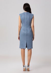 Robe sans manches, près du corps en daim bleu clair avec une fermeture éclair au dos et une fente arrière. Texture lisse avec des coutures sur mesure.