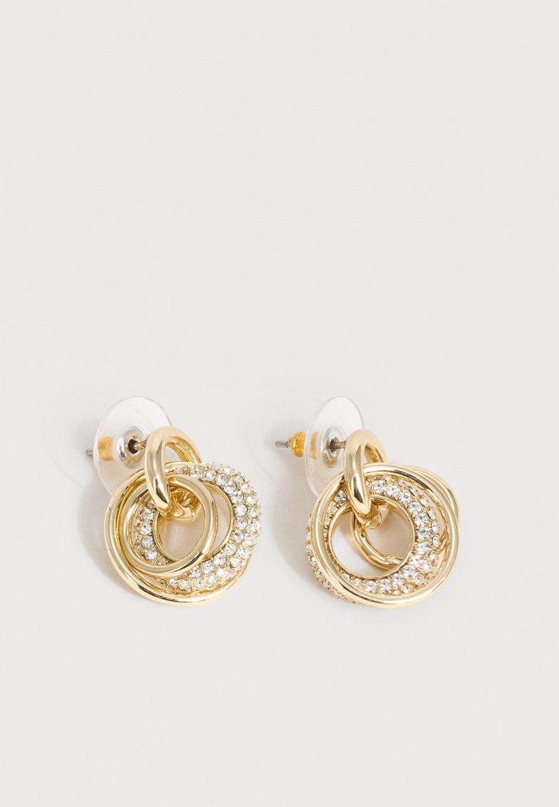 Σκουλαρίκια σε χρυσό τόνο με διασυνδεδεμένους κρίκους, ένας κρίκος διακοσμημένος με μικρούς διάφανους κρυστάλλους, ασφαλισμένοι με διαφανείς πίσω κλειδώματα.