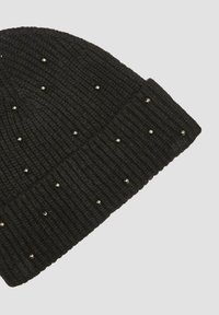Zwarte gebreide beanie met een geribbelde textuur en verspreide metalen studs voor extra detail en accent.