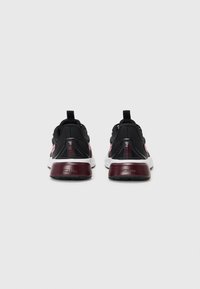 Black athletic shoes with a maroon and white sole, featuring mesh panels, a textured heel, and a pull tab on the back.