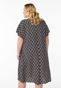 Kurzärmliges, knielanges Kleid aus dunklem Stoff mit einem cremefarbenen, geometrischen Diamantmuster. Es hat eine lockere Silhouette und einen runden Ausschnitt.