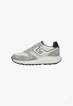Witte en grijze veter sneaker met zwarte zool, suède accenten en een gestileerd "G"-logo aan de zijkant, getoond in profiel.