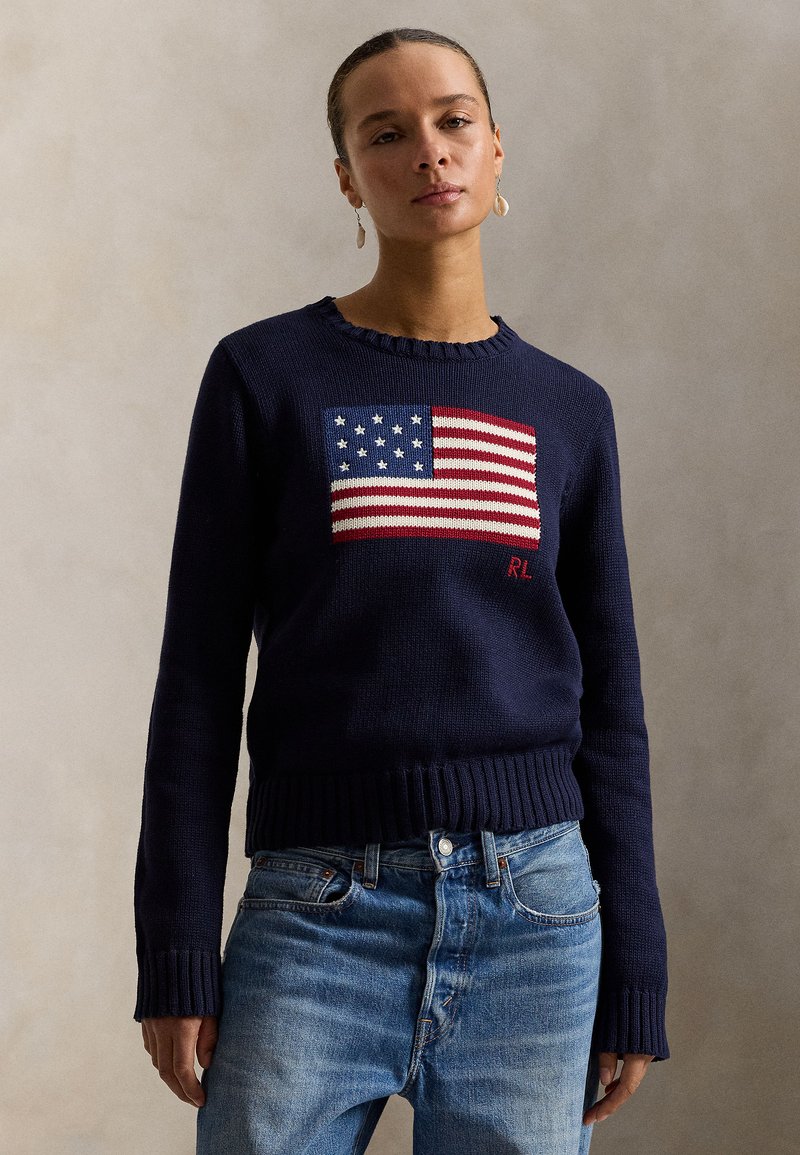 Navy knit sweater featuring a prominently displayed American flag design, ribbed cuffs and hem, with "RL" embroidered in red.
