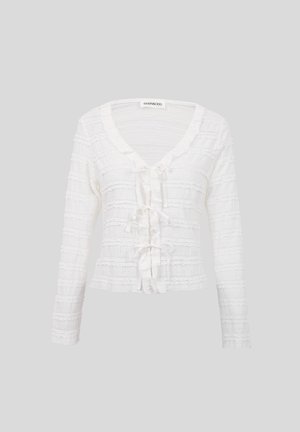 Cardigan blanc à manches longues avec des rayures horizontales en dentelle et trois nœuds attachés sur le devant, doté d'un col arrondi.