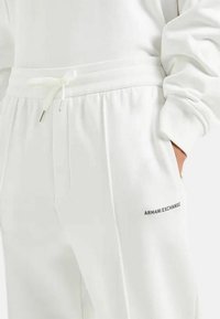Pantaloni della tuta bianchi con vita regolabile tramite coulisse, tasche laterali e logo ricamato "ARMANI EXCHANGE" sulla coscia.