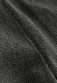 Tissu texturé gris foncé avec un motif de tissage diagonal, présentant des bords lisses et une surface douce. Convient à divers designs vestimentaires.