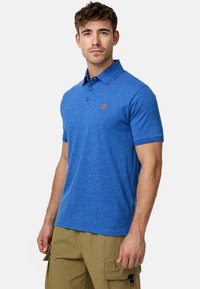 Polo bleu en tissu texturé avec un col à trois boutons, des manches courtes et un petit logo orange sur la poitrine.